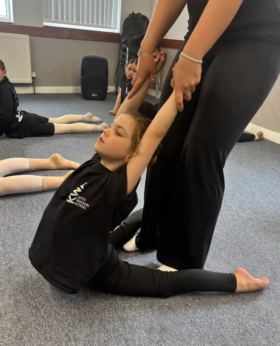 Young student practising acro stretch with a teacher