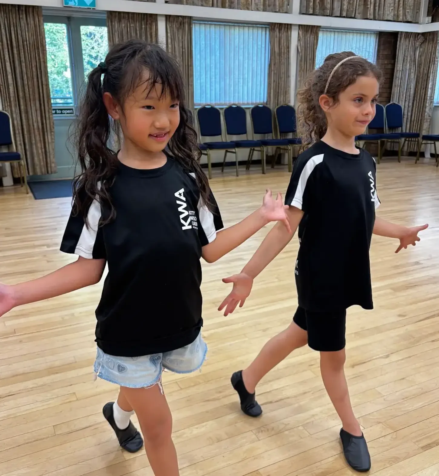 Two young KWA students in black kit dancing in a jazz class