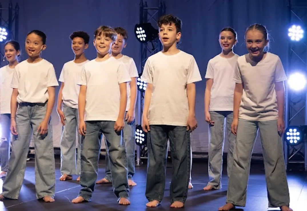 KWA students performing together on stage under stage lighting